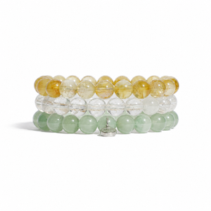 Three stacked beaded bracelets on a white background. The top bracelet is made of translucent golden-yellow beads, the middle is made of clear beads, and the bottom is made of pale mint-green beads.