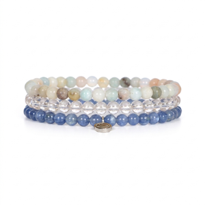 A stack of four beaded stretch bracelets on a white background. The top bracelet features multicolored stone beads in pastel shades of green, beige, and brown.